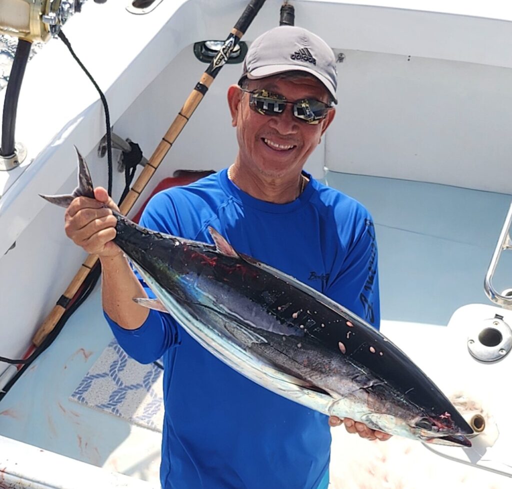 Man holding a large fish on a boat, smiling. Experienced fisherman with a fresh catch on a fishing trip.