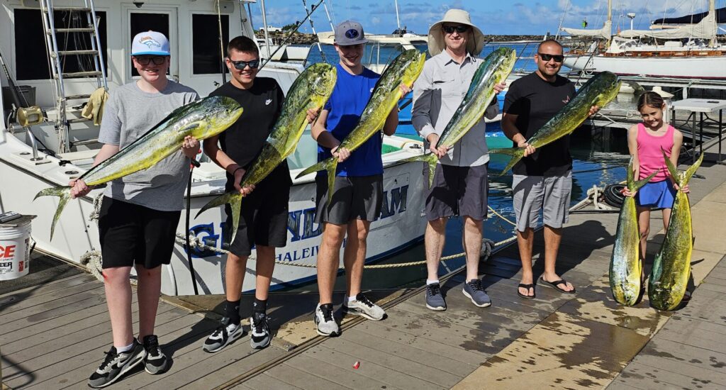 Four men proudly holding large fish on a sunny dock.