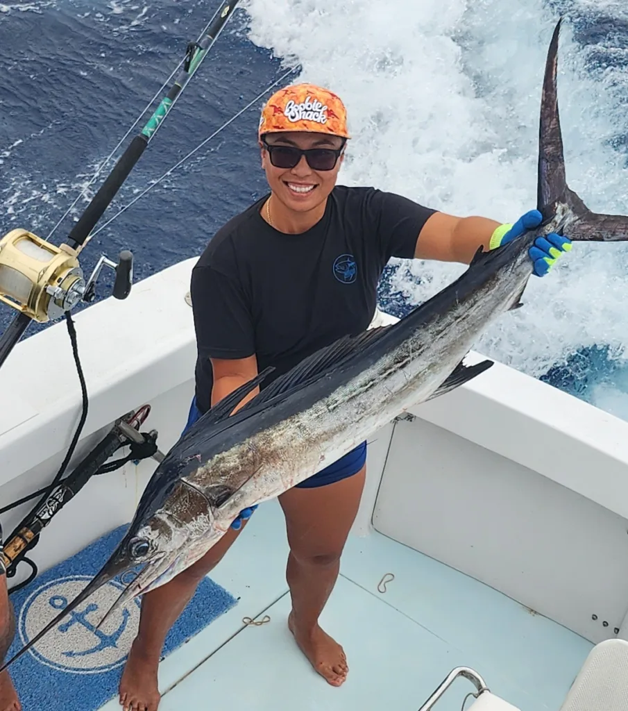 Smiling person holding a large fish on a boat. Catching a prize marlin during a luxury Grand Slam fishing.