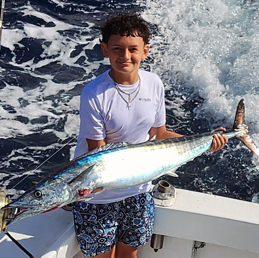 Young boy proudly holding a large fish on a boat. Young angler with a fresh catch on a fishing trip.